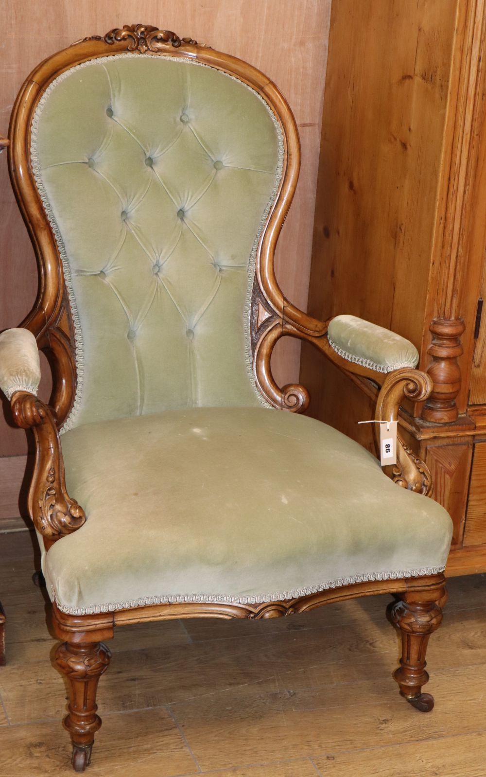 A Victorian deep-buttoned carved walnut open armchair
